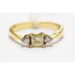 An 18ct gold and diamond three stone ring, central set princess cut 0.45ct of fancy light yellow