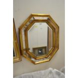 Modern hexagonal gold-painted mirror with a framed print.