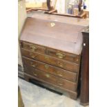 A George III oak bureau with sloping fall front interior with cupboards, pigeon holes and drawers,