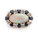 A black opal, sapphire and diamond set oval cluster brooch, the central oval cabochon-cut black opal
