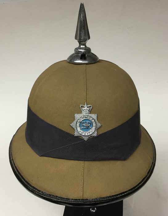 A Bermuda Police Khaki spiked pith helmet complete blue pugree and with Queens Crown cap badge. No