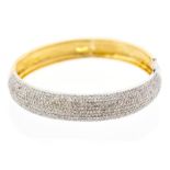 A diamond and 18ct gold hinged bangle, the domed white gold front pave set with brilliant cut