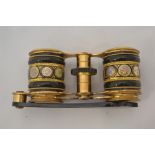 A pair of 19th Century gilt metal and black enamelled opera glasses, the centre decorated with