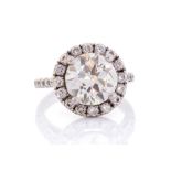 A diamond halo cluster platinum ring, diamond set shoulders, the central round brilliant cut