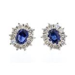 A pair of sapphire and diamond cluster earrings, comprising claw set oval sapphires set to the