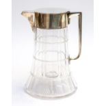 An Edwardian silver mounted large water jug with faceted cut glass body and glass silver mounted
