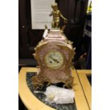 A French, pink marble and gilt bronze clock, bearing a hand painted enamel dial, kneeling cherub