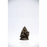 Shiva and familyBronzeIndia18th ctH: 6,5 cmA small statue of a seated Shiva surrounded by his