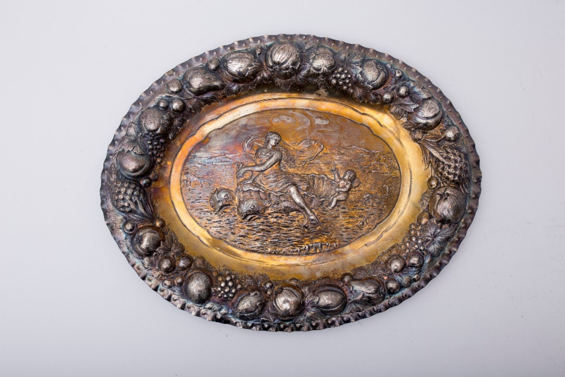 Display plate: Silver, oval-shaped with an embossed scene depicting a goddess riding two dolphins.