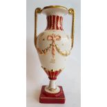 Royal Dux BohemiaSpindle vase; Ceramic with red and gold décor of a flower garland and ribbons.