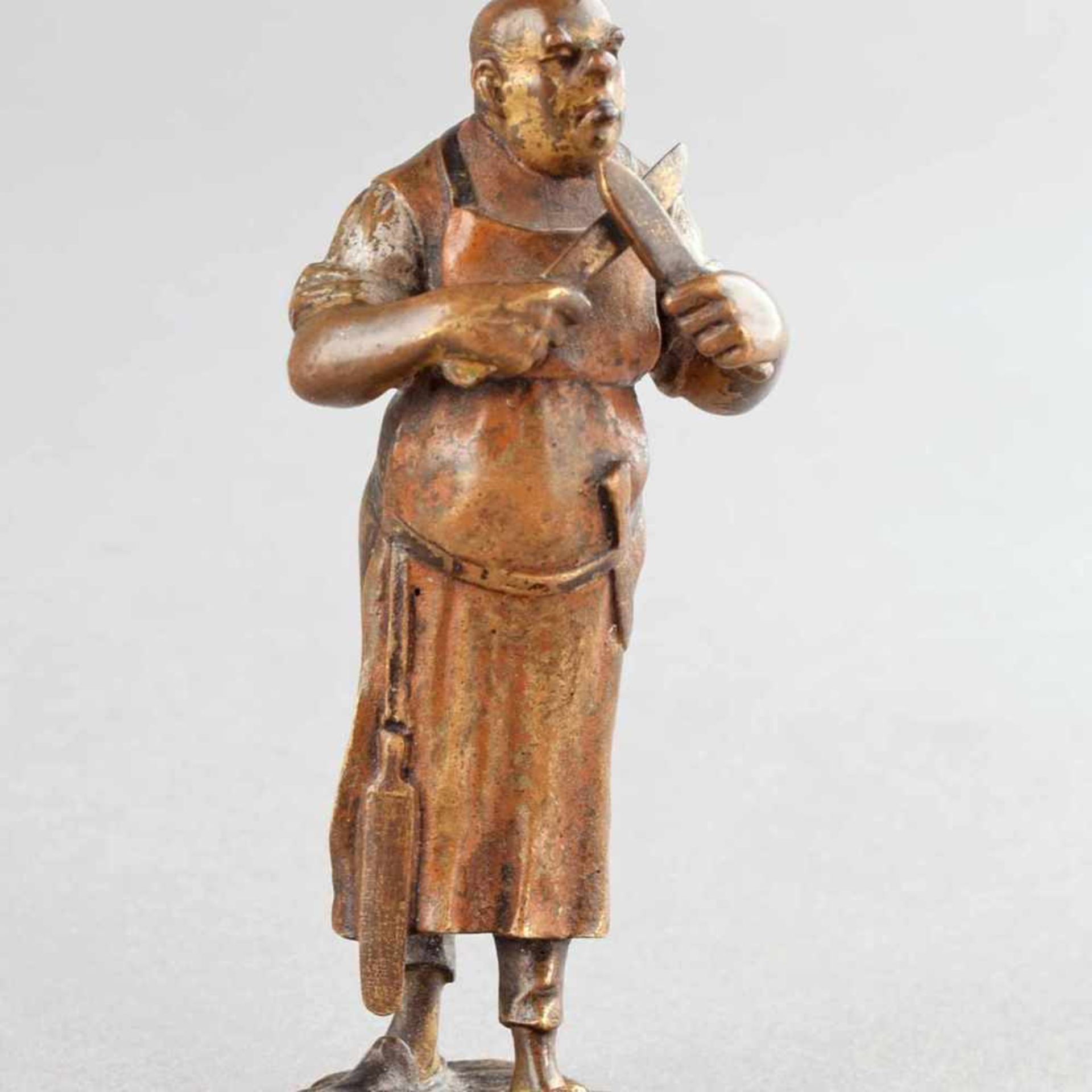 Wiener Bronze Standfigur eines Fleischers mit langer Schürze zwei Messer schärfend, mehrfarbige