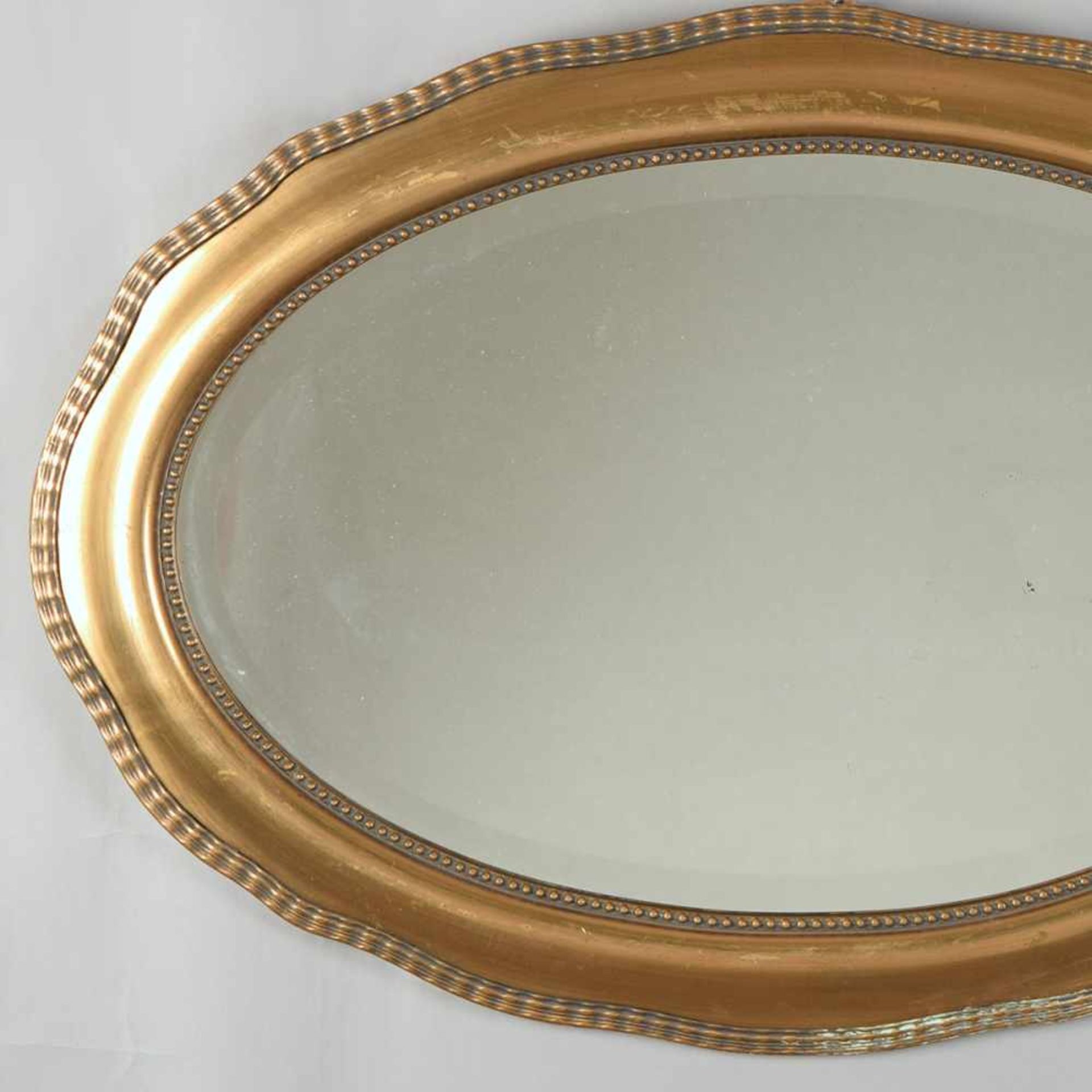 Art déco-Wandspiegel ovale facettierte Spiegelfläche, in geschweifter goldfarbener Profilrahmung mit