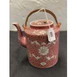 20th cent. Chinese teapot. Rattan handle, pink ground, white and green flowers. 8½ins.