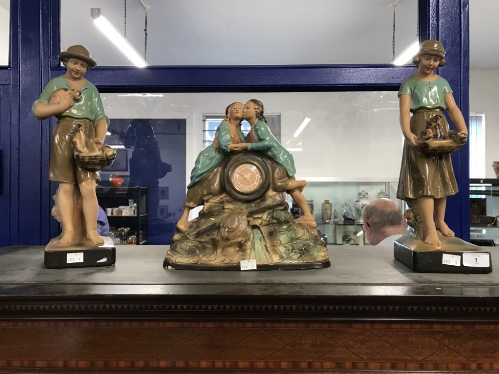 20th cent. Fairground art clock garniture showing 2 lovers kissing and children holding baskets.