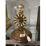 Clock: 20th cent. Brass skeleton clock chiming on the hour, treen base and circular glass dome.