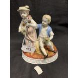 German Porcelain: Oval figure group, a boy with posy the girl playing a mandolin seated on a wheat