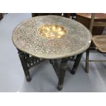Early 20th cent. Anglo Indian beaten brass table with carved folding base. Diameter 36ins.