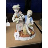 German Porcelain: Oval figure group, a boy with posy the girl playing a mandolin seated on a wheat