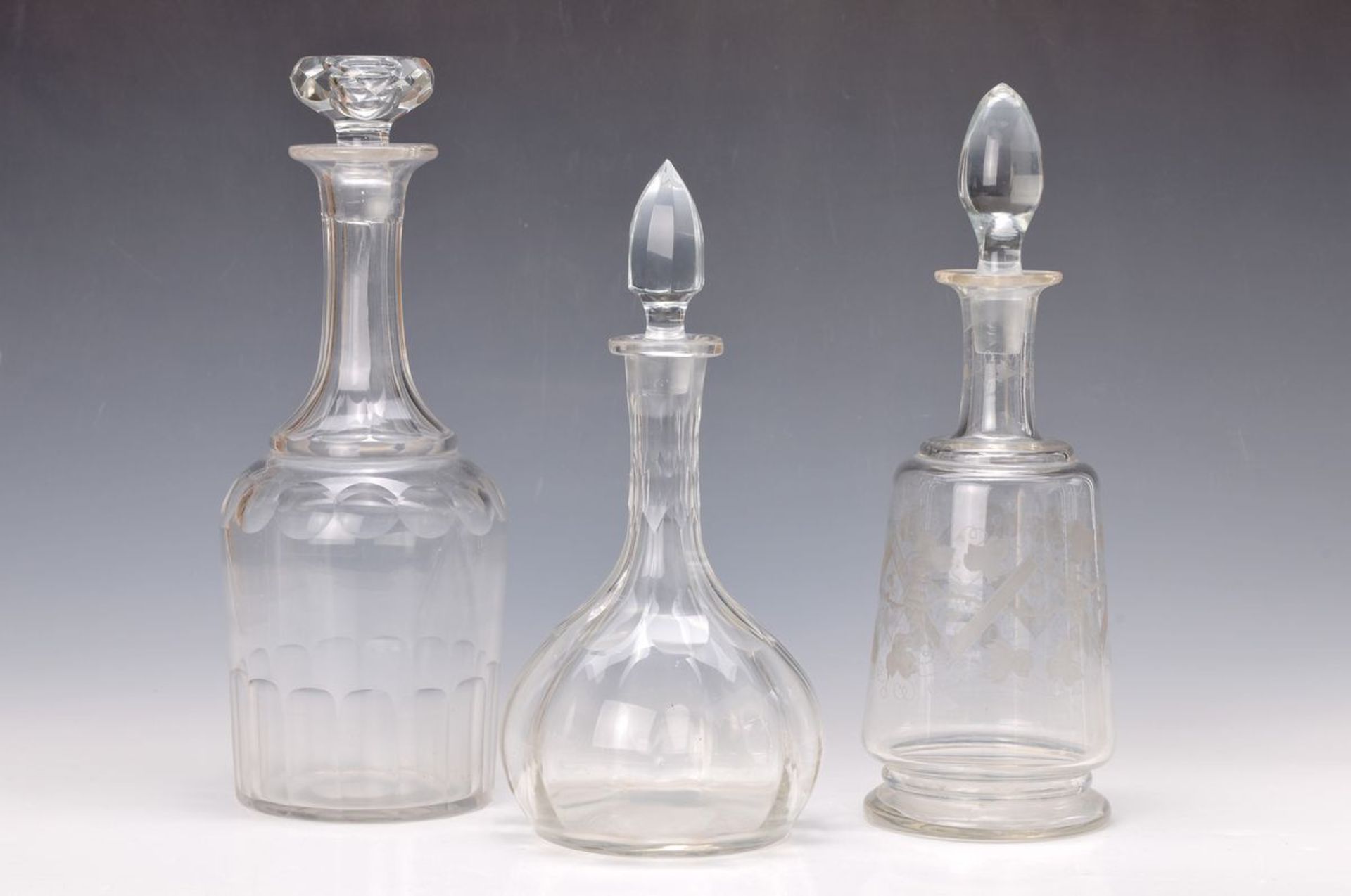 Drei Glaskaraffen, deutsch, um, 1860-1900, farbloses Glas, mit Schälschliff, H. 30-34 cmthree