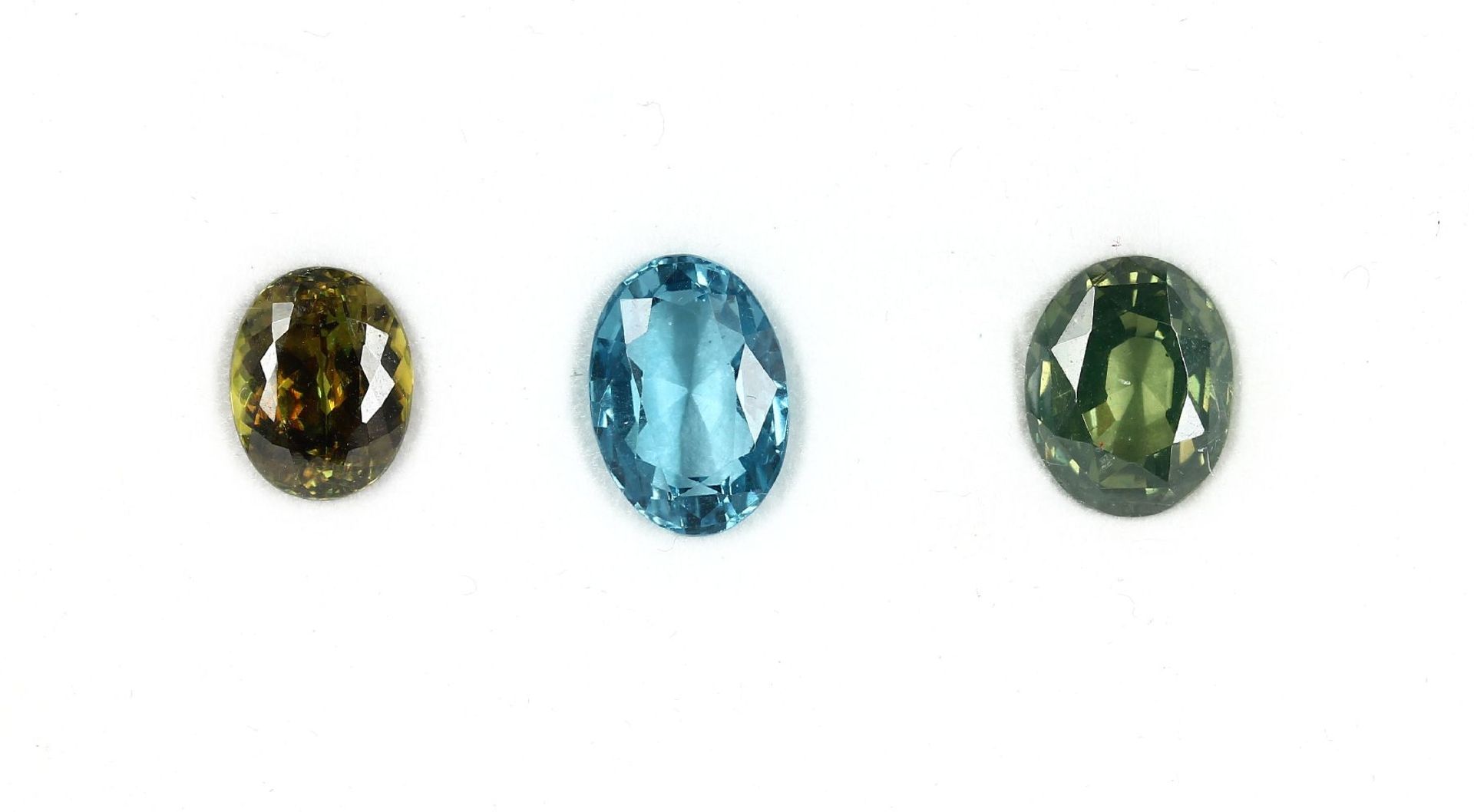 3 lose Zirkone, total ca. 15.18 ct, grün, blau und gelb (beh.)3 loose zircones, total approx. 15.