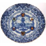 Grootformaat aardewerk wandschotel met blauw-wit en polychroom beschilderd decor: "