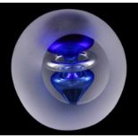 Bolvormig matglazen object met afgeschuinde zijde, waarachter een blauw-wit hartvormige tol, op