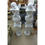 A pair of plaster cherubs and a pair of Italian painted terracotta columns with Putti cherubs