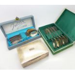 A plated cigarette box and two boxed sets of spoons,