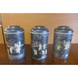 A set of three black chinoiserie metal tea canisters and covers