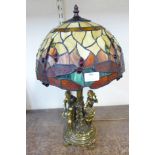 A figural table lamp with Tiffany style shade