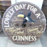 A painted circular wooden Guinness sign