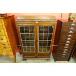 An early 20th Century carved oak tapered two door bookcase