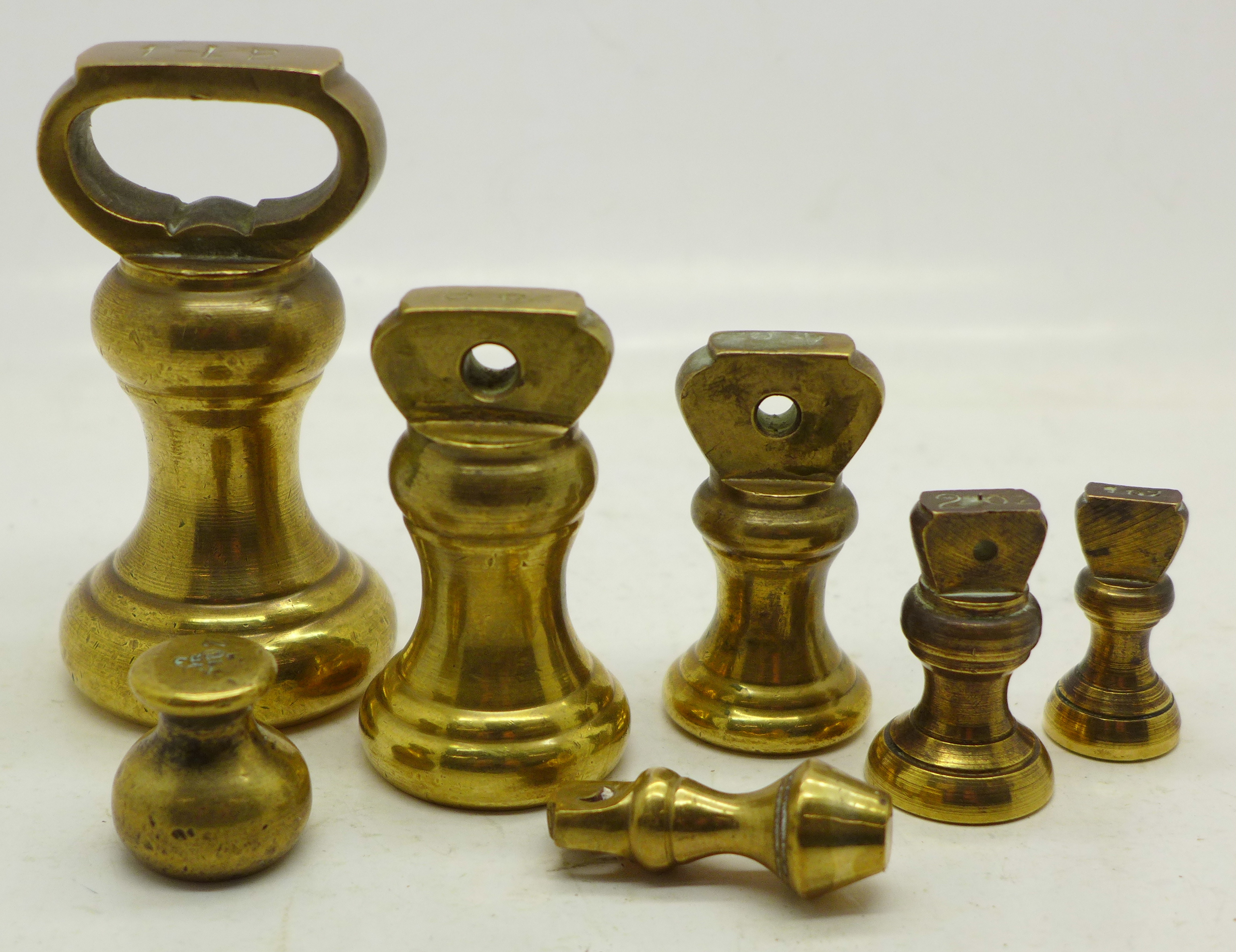 Seven graduated brass bell weights,