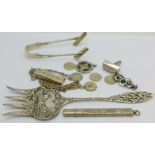 A pair of silver asparagus bows, a silver ingot pendant, a silver pencil holder, a white metal fork,