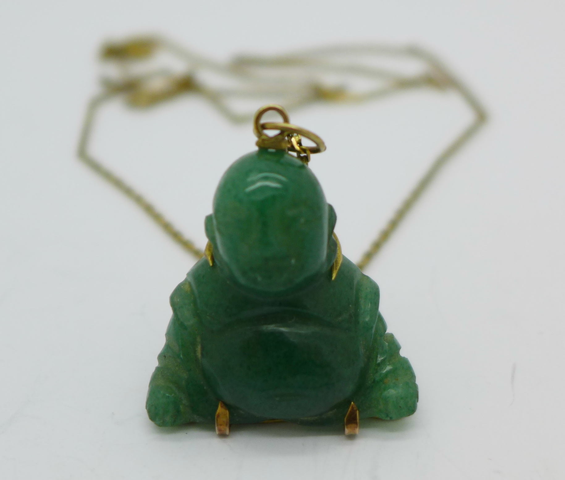 A carved jade Buddha pendant and chain,
