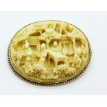 A carved ivory brooch in a yellow metal mount,