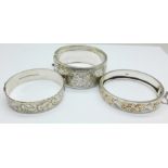 Three silver bangles including one with gold applied decoration,