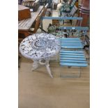 A cast metal table and three folding chairs