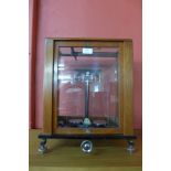 A mahogany and glass cased set of chemist balance scales