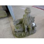 A concrete garden figure of a man on a bench