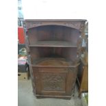 An Arts and Crafts carved oak corner cupboard