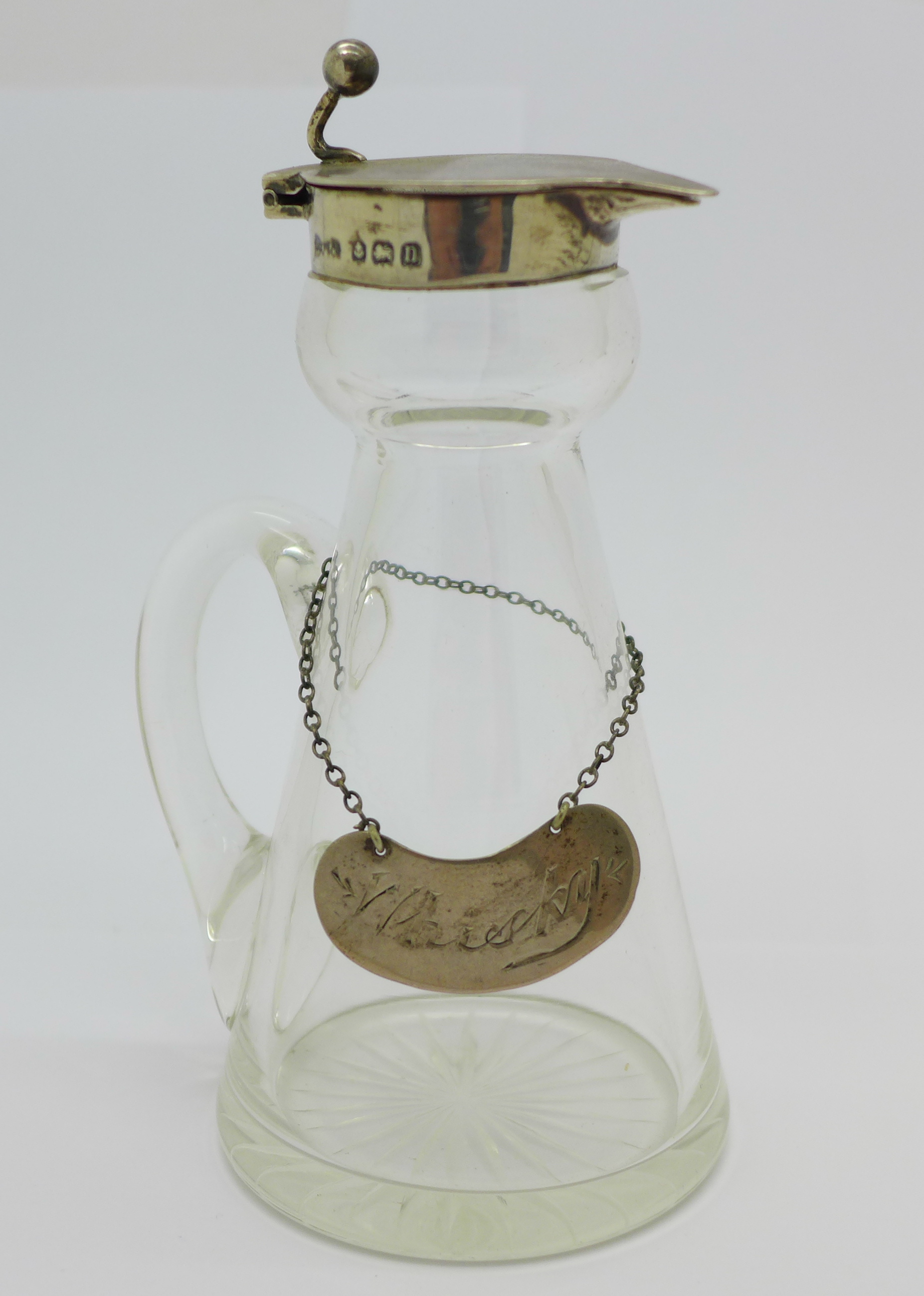 A silver mounted glass whisky noggin with a silver label