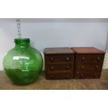 A pair of small mahogany three drawer chests a green glass demijohn