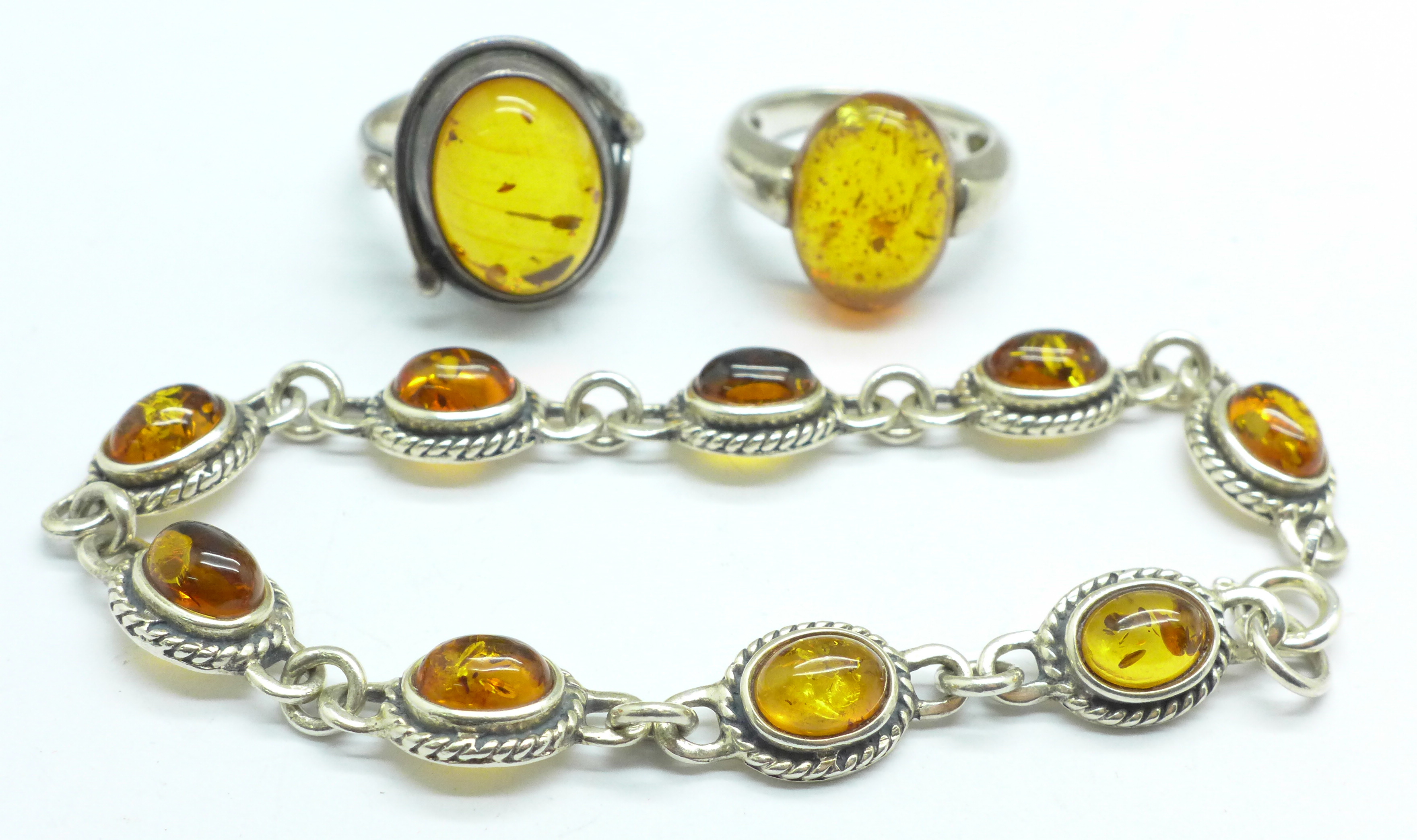 Two silver rings and a bracelet set with amber