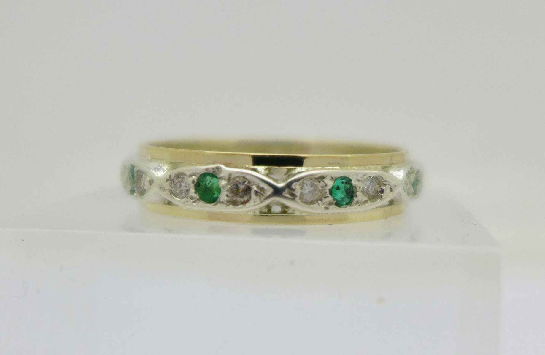 A 9ct gold and silver set emerald and diamond full eternity ring,