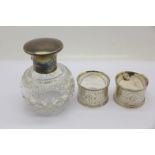 Two silver napkin rings and a silver topped globular glass scent bottle,