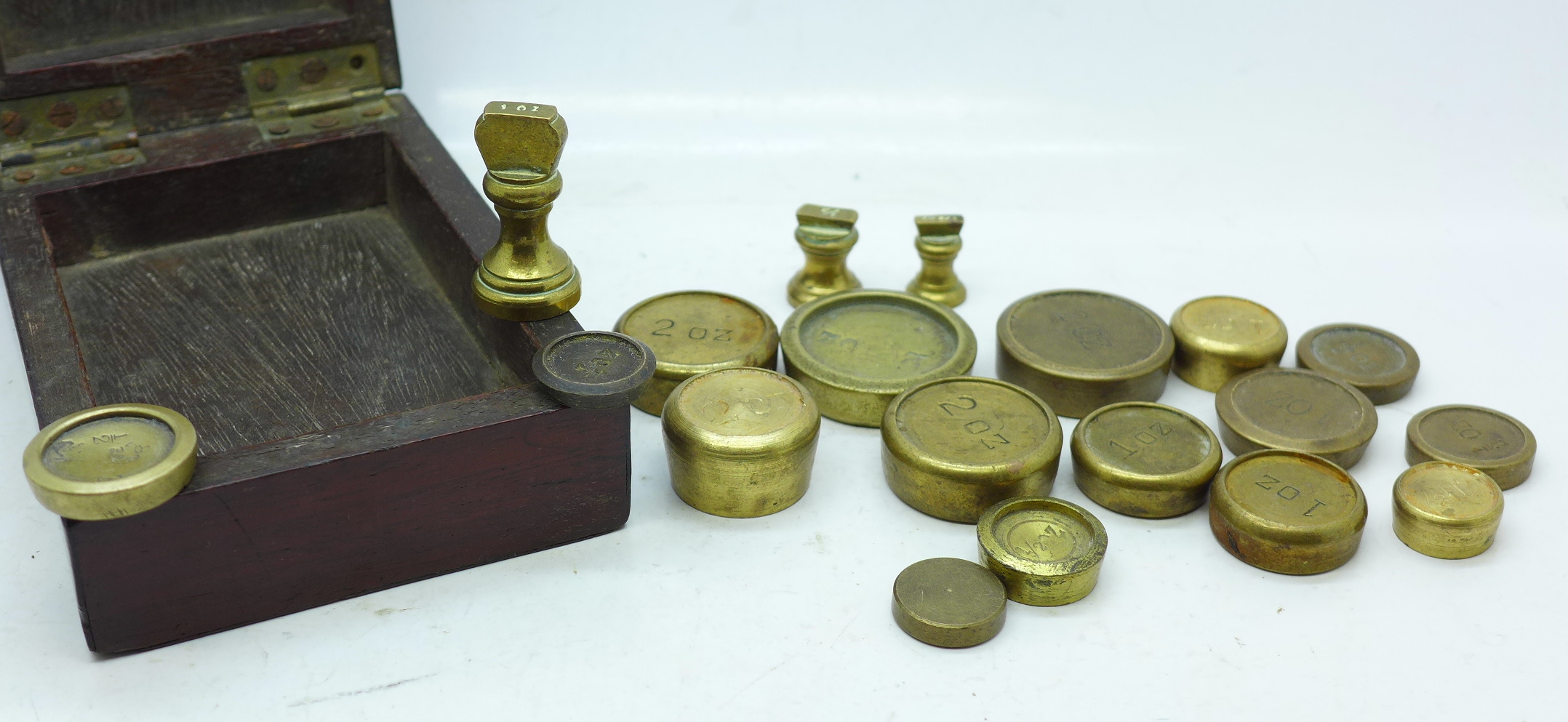 A mahogany box containing nineteen Imperial brass weights