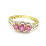 A silver gilt ruby set trilogy ring,