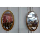A pair of teak framed oval mirrors