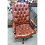 A mahogany and red leather swivel office chair